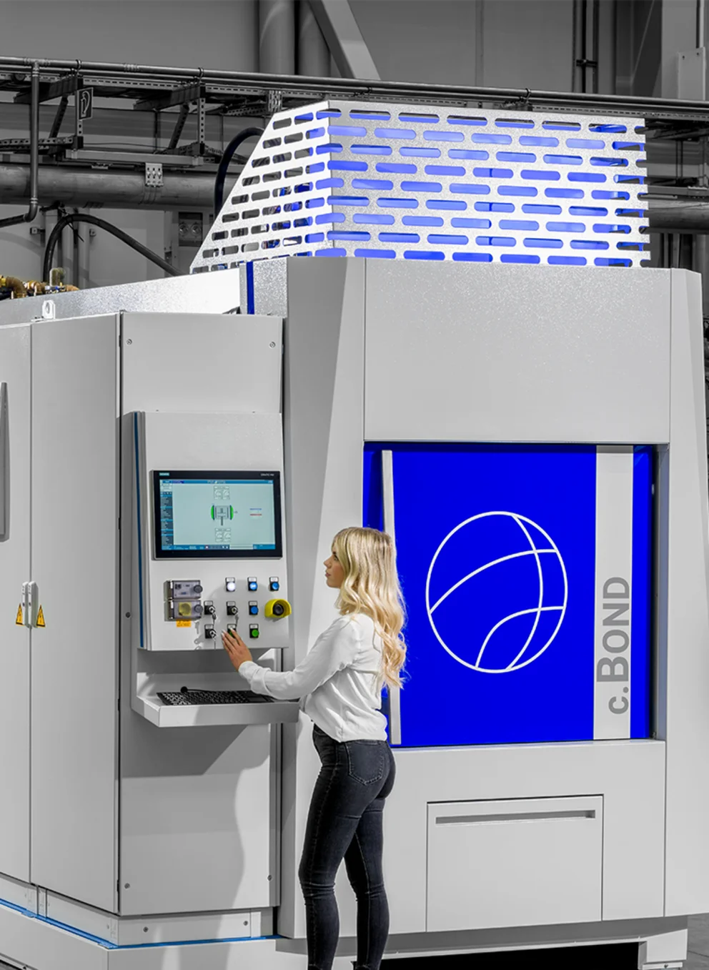 Alu.Bond-Diffusionsschweißofen mit einer Mitarbeiterin am Bedienmonitor.